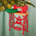 Red sewing machine ornament on a blurred Christmas tree background