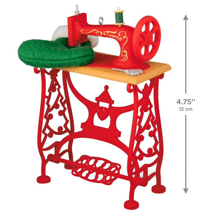 Red toy sewing machine with green presser foot on a white background