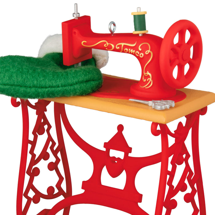 Red toy sewing machine with green fabric on a white background