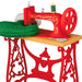 Red toy sewing machine with green fabric on a white background