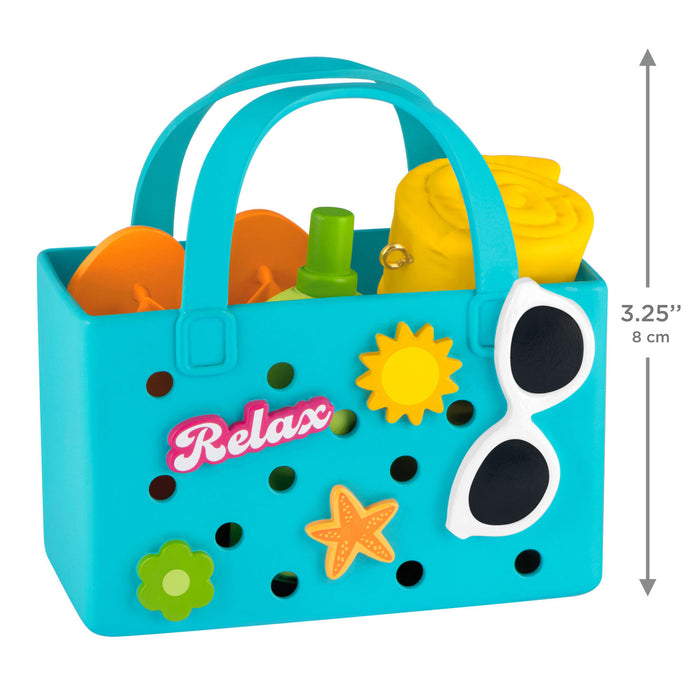 Toy beach bag with sand toys and sunglasses, featuring the word 'Relax'.