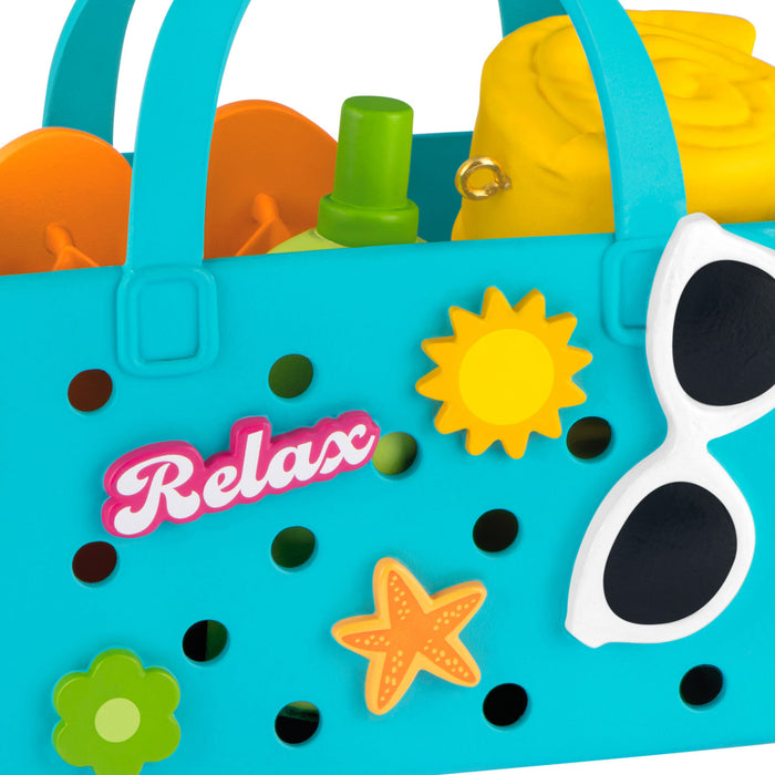 Blue beach bag with 'Relax' text, sunglasses, and beach accessories on a white background