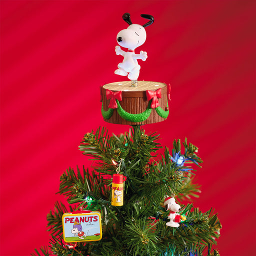 Christmas tree with a Snoopy figurine on top against a red background