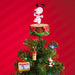 Christmas tree with a Snoopy figurine on top against a red background