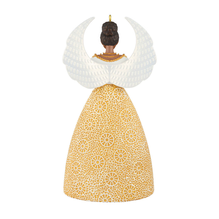 Decorative ornament with a gold patterned dress and white wings on a white background