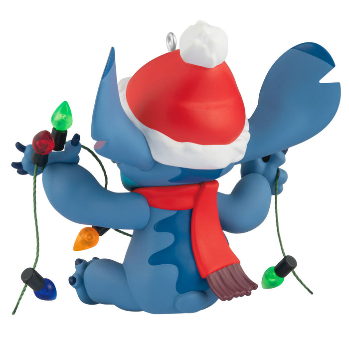 Blue cartoon character with a Santa hat and scarf holding Christmas lights on a white background