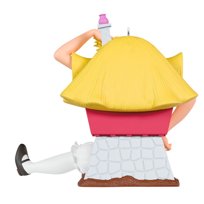 Toy figure of a character with a large yellow hat and pink top, sitting on a white stone block.