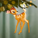 Deer ornament hanging from a tree with a blurred green background