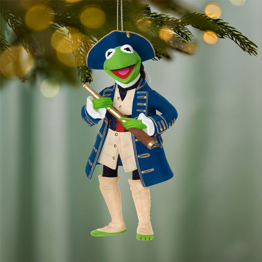 Decorative ornament of a green character in a blue coat and hat holding a telescope, hanging from a tree.