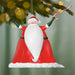 Santa Claus Christmas ornament hanging from a tree with blurred lights in the background