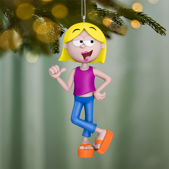 Cartoon character ornament with yellow hair, purple shirt, blue pants, and orange sandals hanging from a Christmas tree.