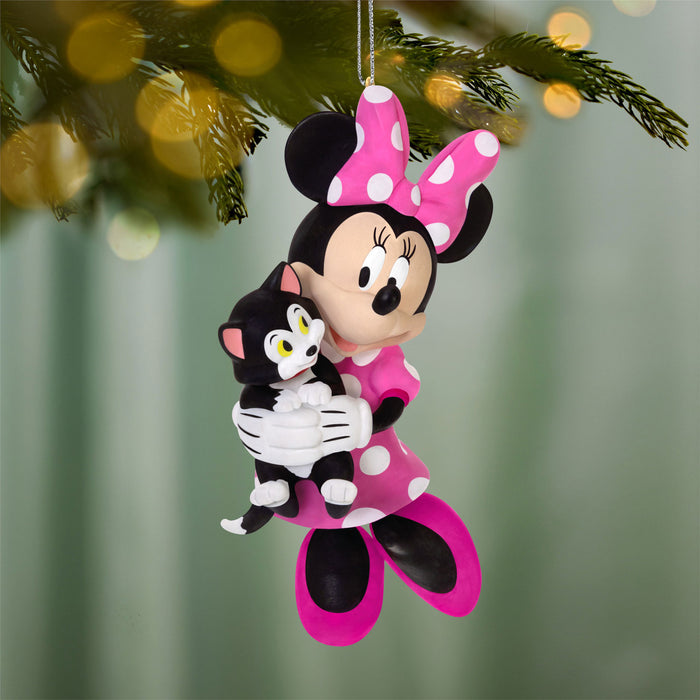 Minnie Mouse ornament holding a black cat, hanging on a Christmas tree.