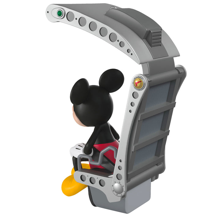 Toy figure of a character with mouse ears sitting in a gray vehicle on a white background