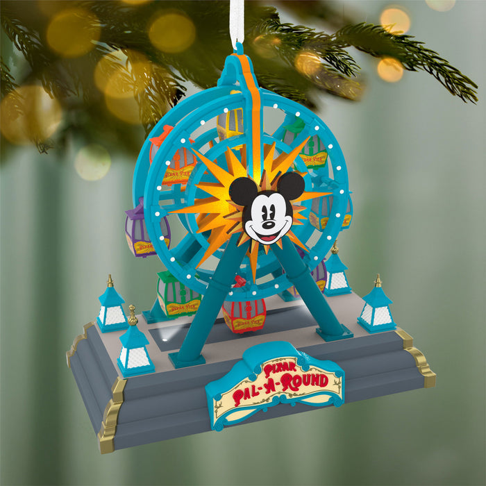 Decorative Christmas ornament resembling a Ferris wheel with Mickey Mouse face, hanging on a tree.