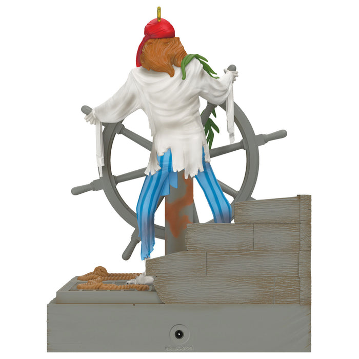 Pirate figurine on a ship's wheel with a white shirt, blue pants, and red hat.
