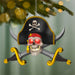Pirate-themed Christmas ornament with skull, crossbones, and swords on a blurred green background.