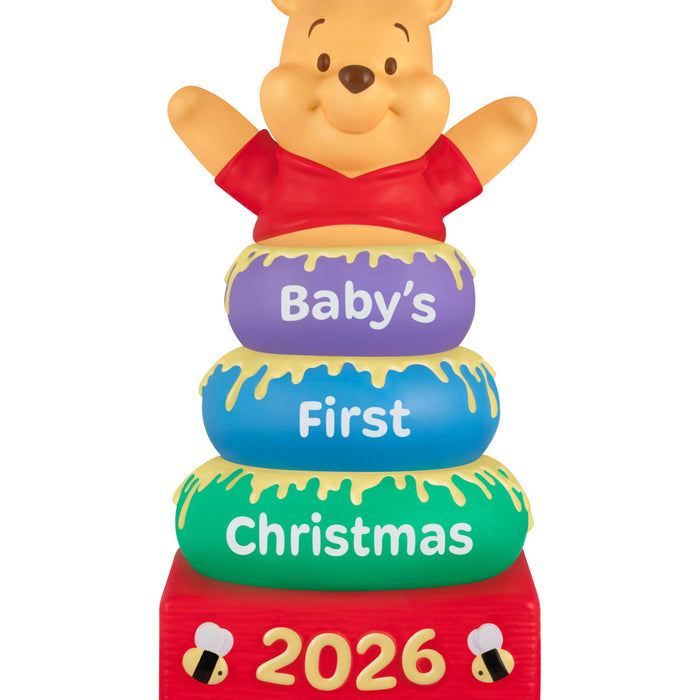 Stack of colorful rings with Winnie the Pooh, 'Baby's First Christmas 2026' text on a white background