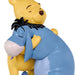 Close-up of a figurine of Winnie the Pooh hugging Eeyore on a white background