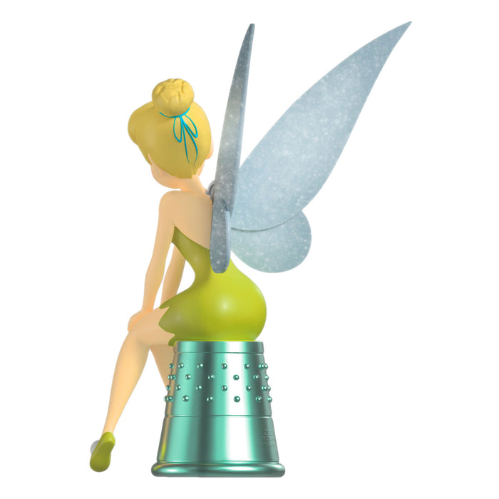 Tinker Bell figurine sitting on a silver canister with green dress and blue hair bow.