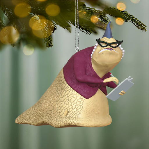 Decorative ornament of a sloth wearing glasses and a sweater, hanging from a Christmas tree.