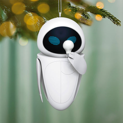 White robot ornament with blue eyes hanging on a Christmas tree.