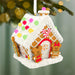 Decorative gingerbread house ornament with candy details on a blurred Christmas tree background