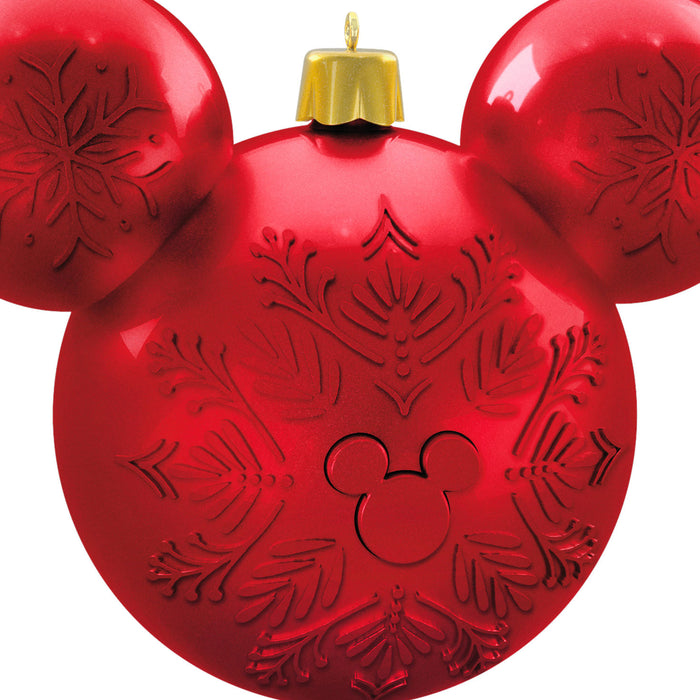 Red ornament shaped like a Mickey Mouse head with snowflake patterns on a white background