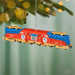 Colorful train ornament hanging on a Christmas tree with a blurred green background