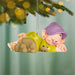 Animated character ornament hanging from a Christmas tree with blurred lights in the background