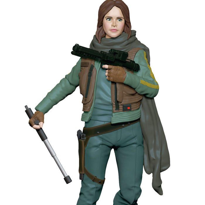 Action figure of a character in a green and brown outfit holding weapons on a white background