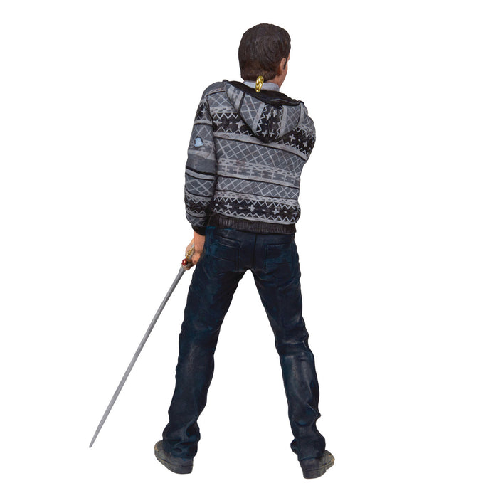 Person wearing a patterned hoodie and dark jeans holding a cane on a white background