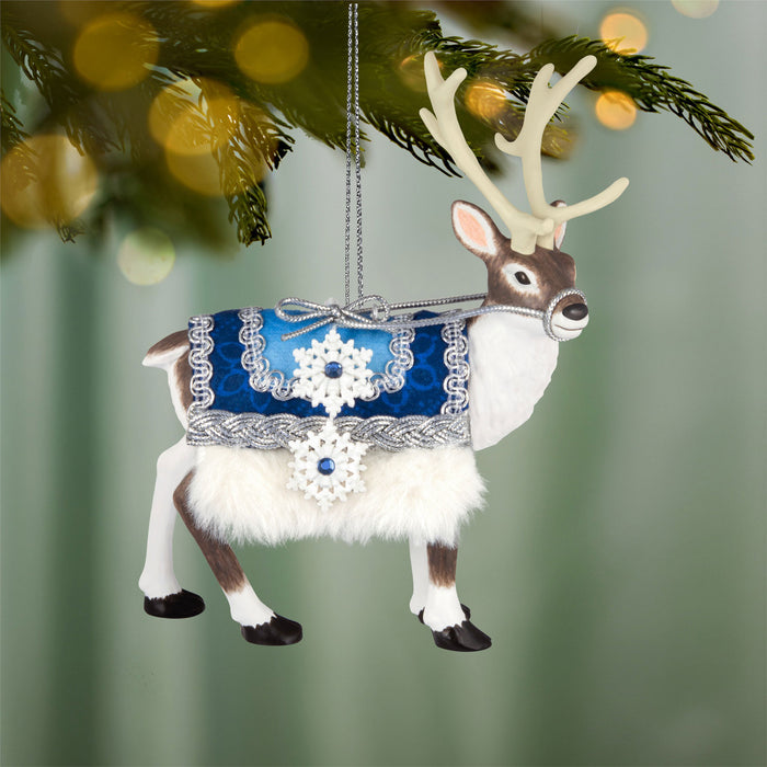 Decorative reindeer ornament with a blue and silver outfit hanging on a tree.