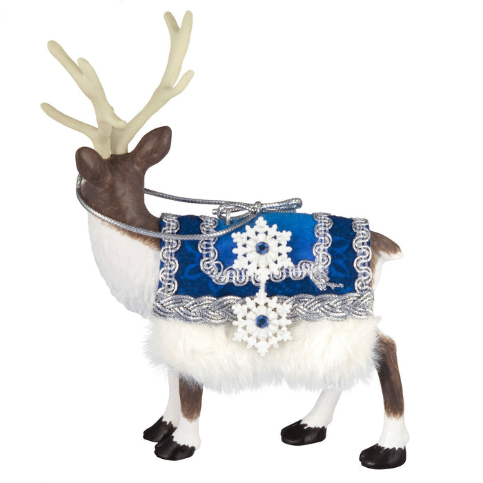 Decorative reindeer figure wearing a blue and white patterned harness on a white background