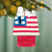 Snoopy on a wooden American flag doghouse  ornament with a blurred Christmas tree background