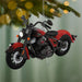 Red and black motorcycle ornament hanging on a Christmas tree with blurred lights in the background.
