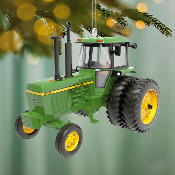 Green tractor ornament with yellow wheels hanging on a Christmas tree.