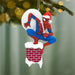 Spider-Man Christmas ornament climbing a chimney with a blurred Christmas tree background