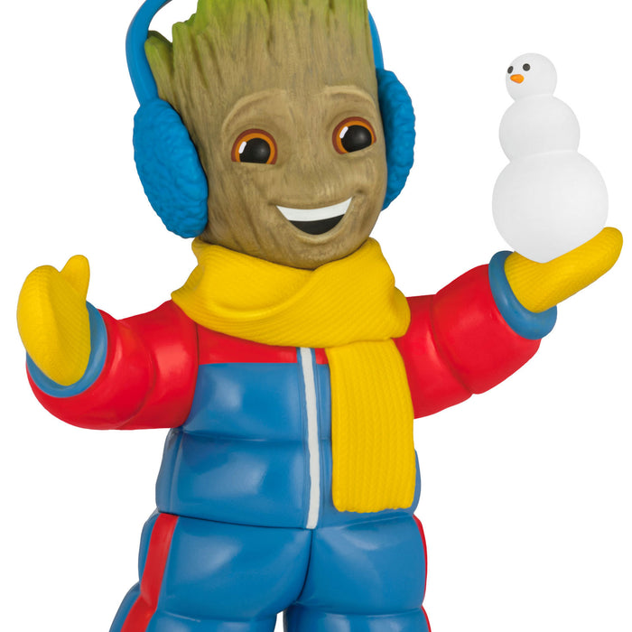 Toy figure of a character in colorful winter clothing holding a snowman.