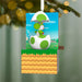 Decorative ornament featuring a green dinosaur-like character in an egg, hanging from a tree.