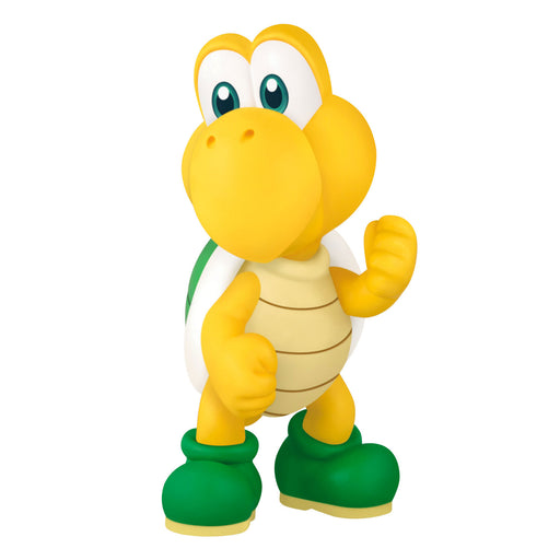 Toy figure of a yellow turtle with green boots on a white background