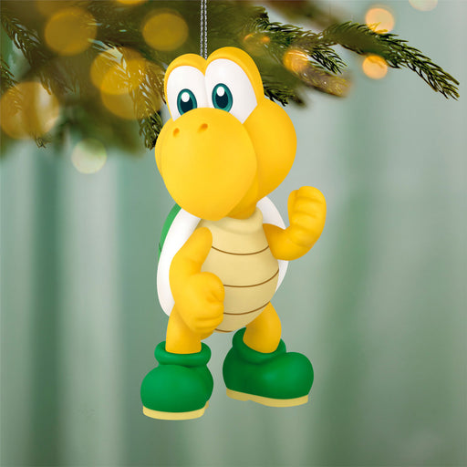 Yellow turtle-like character ornament hanging on a Christmas tree with blurred lights in the background