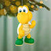 Yellow turtle-like character ornament hanging on a Christmas tree with blurred lights in the background