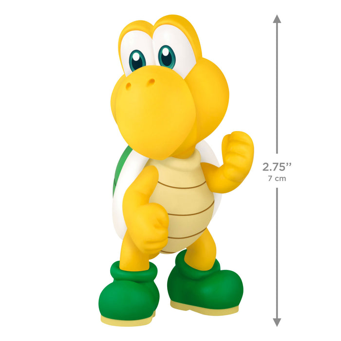 Toy figure of a yellow character with green boots, with a measurement label on a white background.