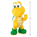 Toy figure of a yellow character with green boots, with a measurement label on a white background.