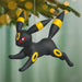Black and yellow Umbreon Pokémon ornament hanging on a Christmas tree.