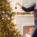 Person decorating a Christmas tree with Poké Ball ornaments.