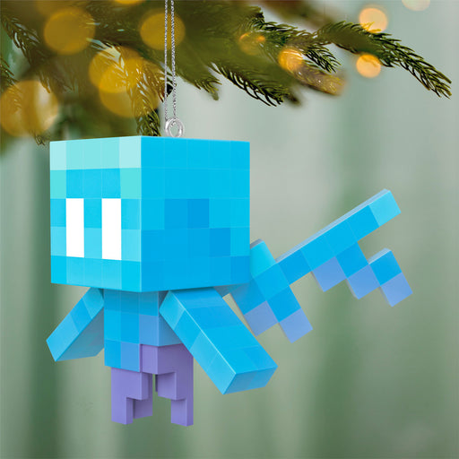 Blue pixelated character ornament hanging on a Christmas tree.