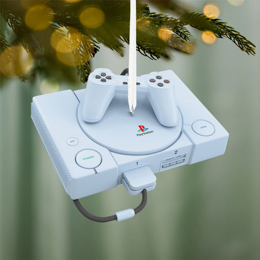 PlayStation console ornament hanging on a Christmas tree with blurred lights in the background
