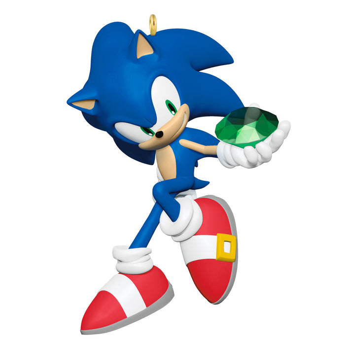 Blue animated character with red shoes holding a green gem on a white background