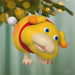 Colorful cartoon figure ornament hanging on a Christmas tree with blurred lights in the background